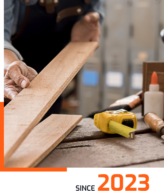 A person measures a wooden plank with a tape measure on a workbench, surrounded by tools and glue bottles. The text Since 2023 appears at the bottom.